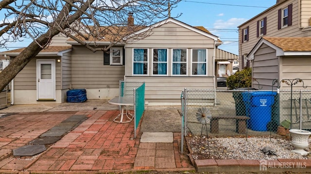 back of house with a chimney, a patio, and fence