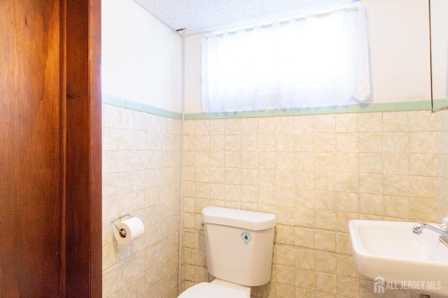 2624 Tremley Point Rd, Linden, NJ 07036 - bathroom featuring toilet, tile walls, a sink, a textured ceiling, and a wainscoted wall