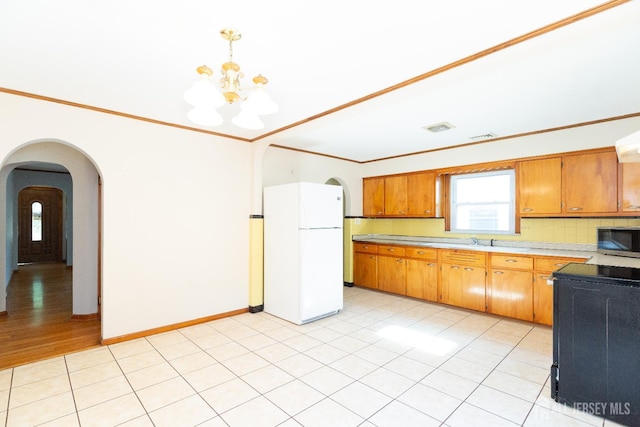 2624 Tremley Point Rd, Linden, NJ 07036 - kitchen featuring freestanding refrigerator, stainless steel microwave, a chandelier, light countertops, and arched walkways
