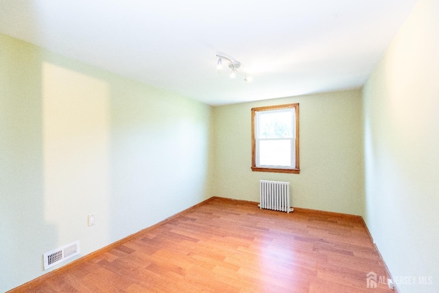 2624 Tremley Point Rd, Linden, NJ 07036 - empty room with radiator, wood finished floors, rail lighting, and baseboards