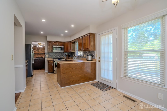55 Cambridge Way, West Windsor, NJ 08550 - kitchen featuring stainless steel appliances, a sink, tasteful backsplash, a peninsula, and light tile patterned floors