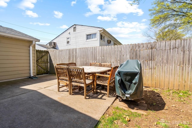 view of patio with outdoor dining space, a fenced backyard, area for grilling, and a gate