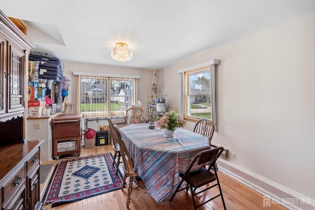dining space with a chandelier, healthy amount of natural light, wood finished floors, and baseboards