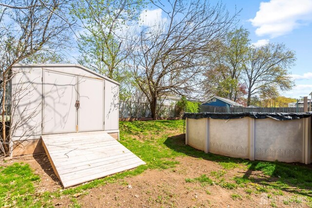 view of yard with a storage unit, fence, an outdoor structure, and a covered pool