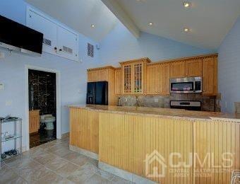 kitchen featuring appliances with stainless steel finishes, beamed ceiling, kitchen peninsula, high vaulted ceiling, and decorative backsplash