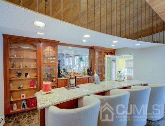 kitchen with a high ceiling, a healthy amount of sunlight, built in features, and light stone countertops