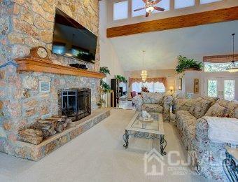 living room featuring beamed ceiling, a fireplace, ceiling fan, and a healthy amount of sunlight