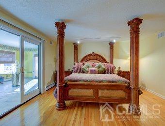 bedroom featuring a textured ceiling, baseboard heating, hardwood / wood-style floors, and access to outside