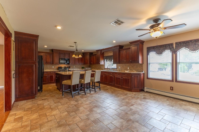 23 Little Brook Ln, Monroe, NJ 08831 - kitchen with black appliances, light countertops, a sink, a breakfast bar, and backsplash