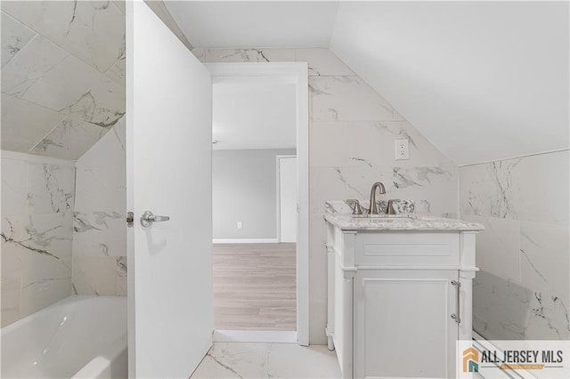 bathroom featuring marble finish floor, vanity, and vaulted ceiling