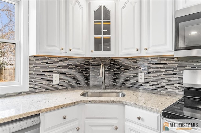 kitchen featuring glass insert cabinets, white cabinets, dishwasher, a sink, and decorative backsplash