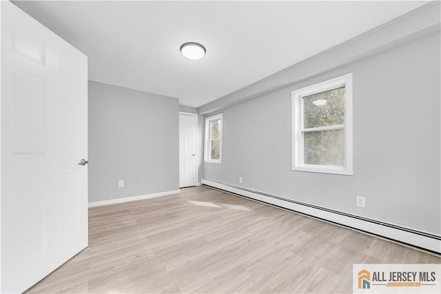 spare room with light wood-style floors, a baseboard radiator, and baseboards