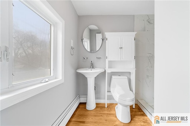 bathroom with toilet, a baseboard radiator, wood finished floors, and a healthy amount of sunlight