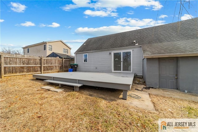 back of house with fence, a deck, and roof with shingles