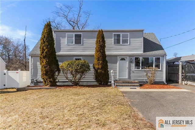 view of front of house with a front yard, a gate, roof with shingles, and fence