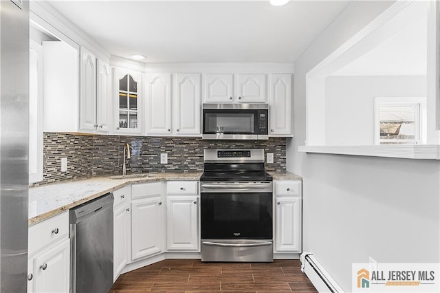 kitchen with glass insert cabinets, a sink, white cabinetry, wood finish floors, and stainless steel appliances
