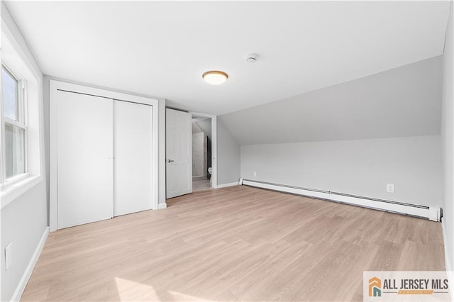 additional living space featuring baseboard heating, light wood finished floors, and baseboards