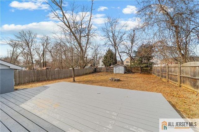 wooden terrace with an outbuilding, a fenced backyard, a yard, and a storage unit