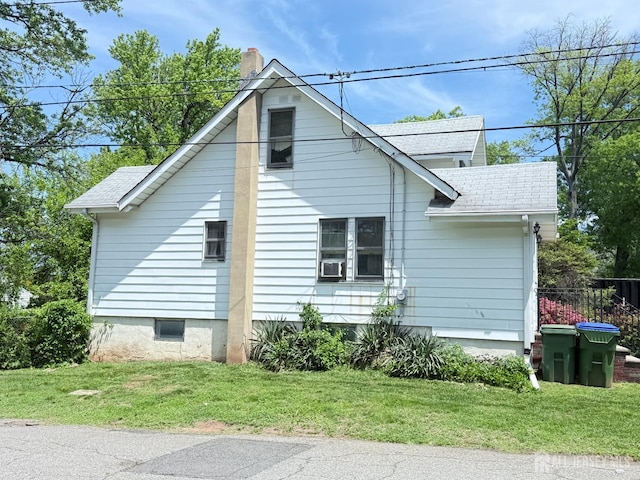 view of side of home featuring roof with shingles, a chimney, and a yard