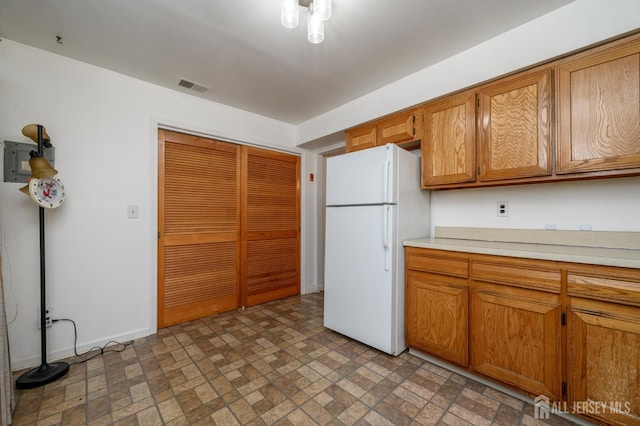101 Mandon Ct Unit 4, South Brunswick, NJ 08540 - kitchen with freestanding refrigerator, brick patterned floors, light countertops, brown cabinets, and baseboards