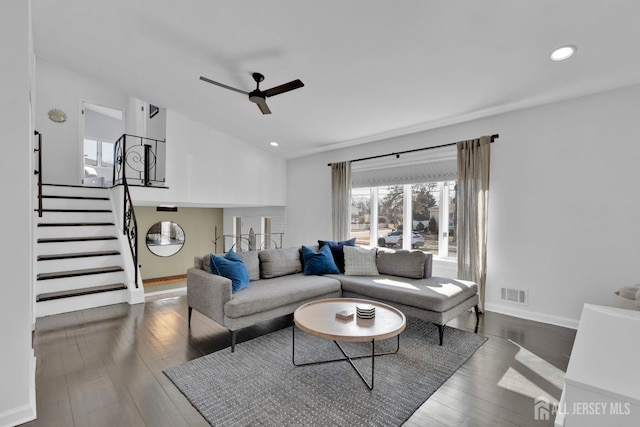 living area featuring ceiling fan, visible vents, vaulted ceiling, stairway, and dark wood finished floors