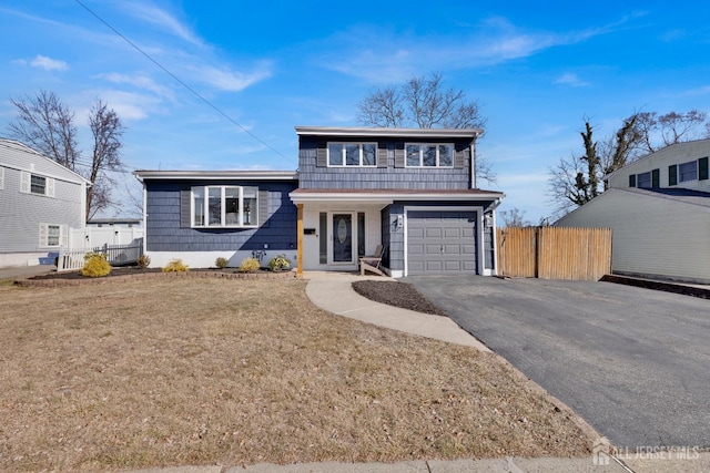 view of front of home with a garage, driveway, a front lawn, and fence