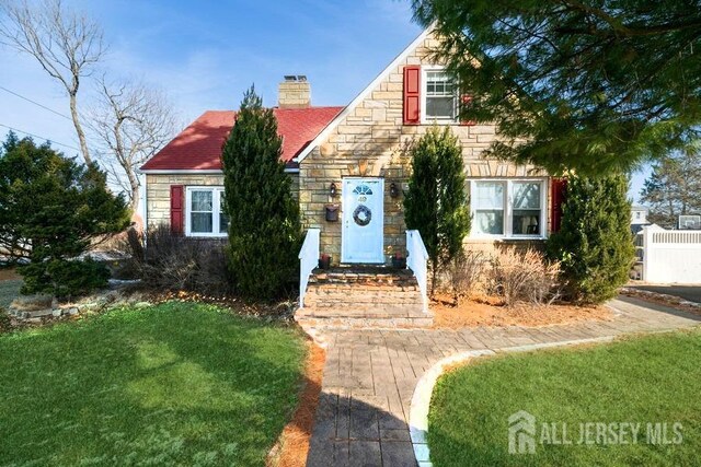 bungalow-style home with a chimney, a front lawn, and stone siding