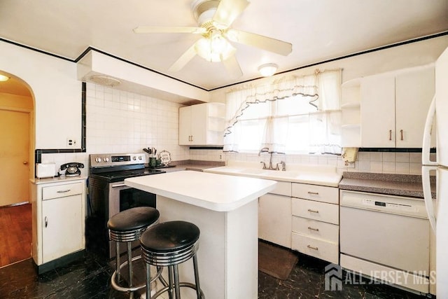 kitchen with a sink, a kitchen bar, a ceiling fan, white appliances, and open shelves