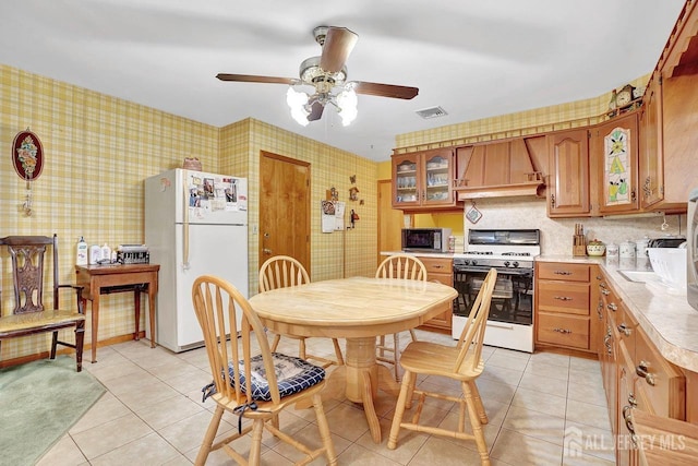 kitchen featuring white appliances, visible vents, light countertops, wallpapered walls, and custom range hood