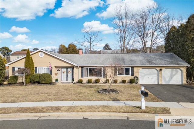 ranch-style house with a garage, a chimney, aphalt driveway, french doors, and a front lawn