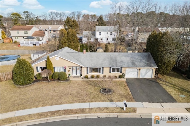 view of front of home featuring aphalt driveway, a chimney, an attached garage, and a residential view