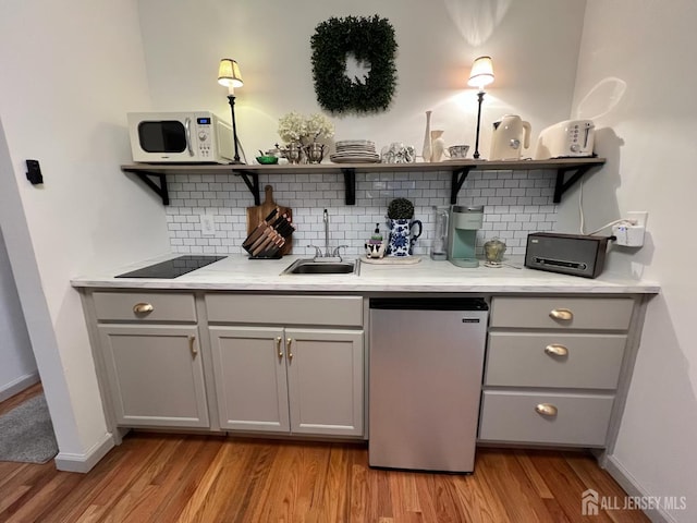 520 Albermarle St, Rahway, NJ 07065 - bar area featuring refrigerator, black electric stovetop, white microwave, light wood-style floors, and tasteful backsplash