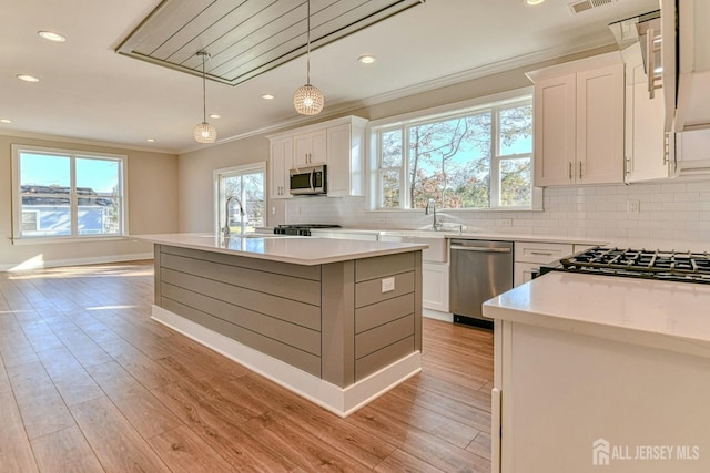 1032 3rd Ave, Manchester, NJ 08757 - kitchen featuring appliances with stainless steel finishes, crown molding, white cabinets, decorative backsplash, and light wood-type flooring