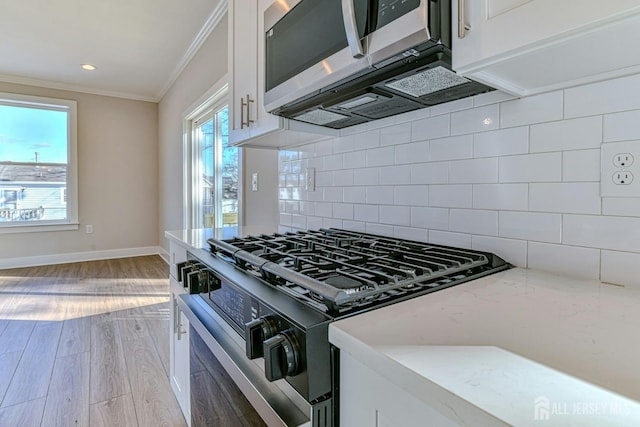 1032 3rd Ave, Manchester, NJ 08757 - kitchen with black range with gas cooktop, stainless steel microwave, ornamental molding, white cabinetry, and decorative backsplash
