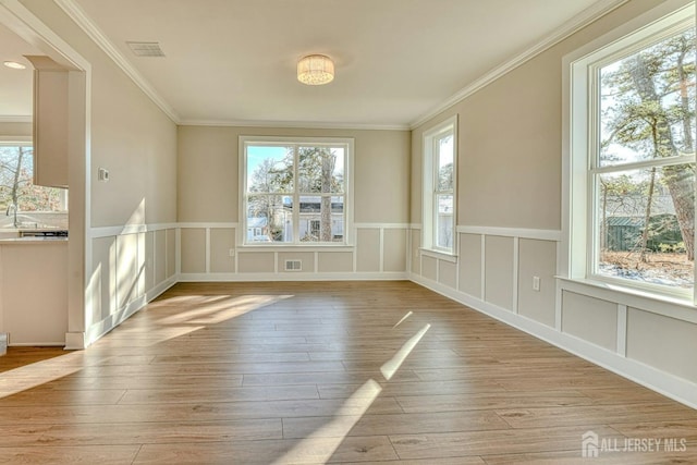 1032 3rd Ave, Manchester, NJ 08757 - empty room with plenty of natural light, light wood-style flooring, ornamental molding, a decorative wall, and wainscoting