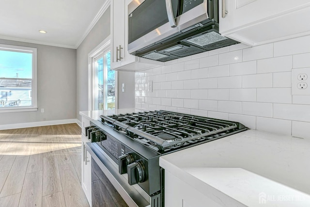 1032 3rd Ave, Manchester, NJ 08757 - kitchen with gas range oven, crown molding, white cabinets, light wood finished floors, and decorative backsplash