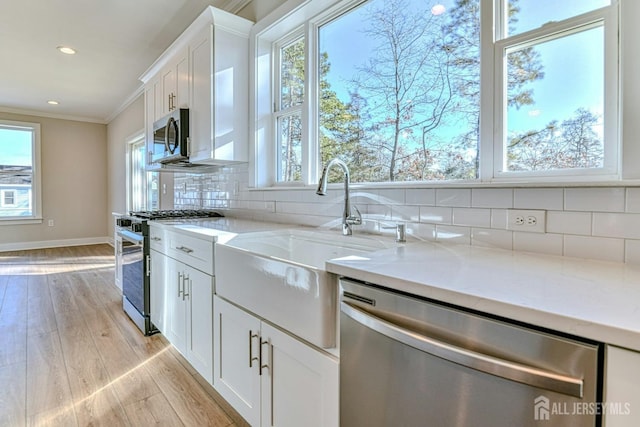 1032 3rd Ave, Manchester, NJ 08757 - kitchen featuring appliances with stainless steel finishes, light wood-style floors, decorative backsplash, white cabinets, and ornamental molding