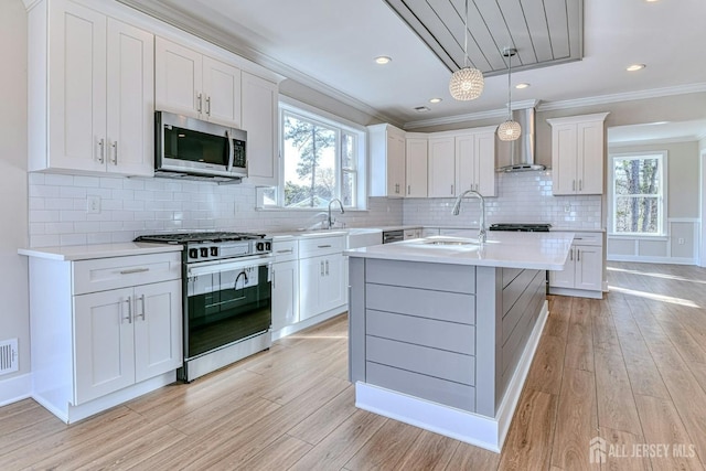 1032 3rd Ave, Manchester, NJ 08757 - kitchen with stainless steel appliances, wall chimney range hood, a sink, light wood finished floors, and crown molding