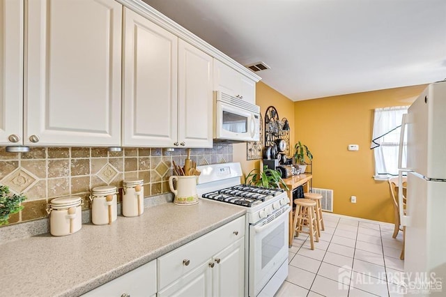 kitchen with white appliances, visible vents, white cabinets, light countertops, and backsplash