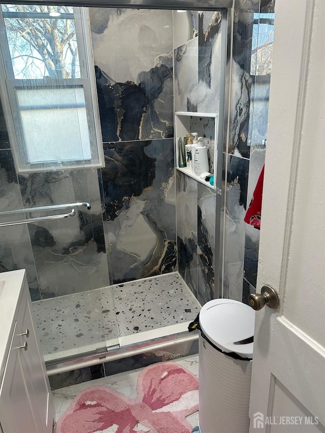 full bathroom featuring a marble finish shower and vanity