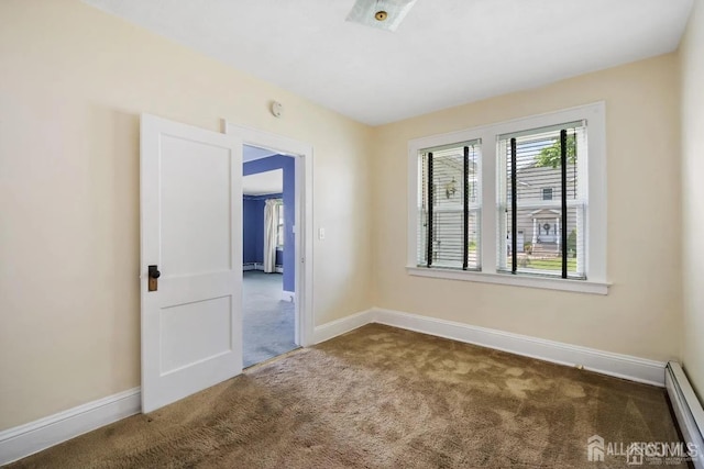 carpeted empty room featuring a baseboard heating unit and baseboards