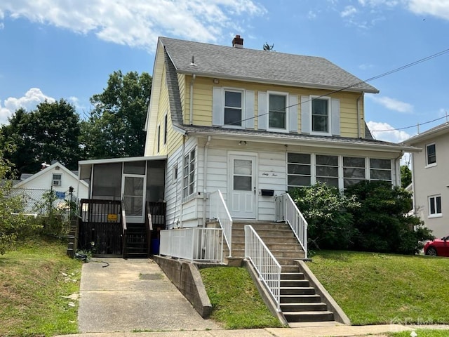 view of front of property featuring a sunroom and a front lawn