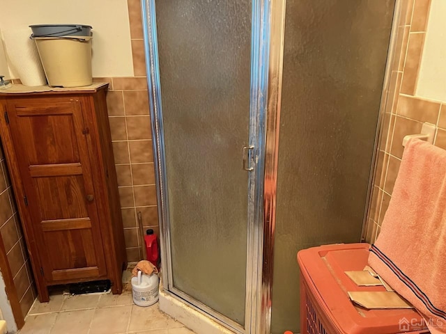 bathroom with tile patterned floors, an enclosed shower, and tile walls