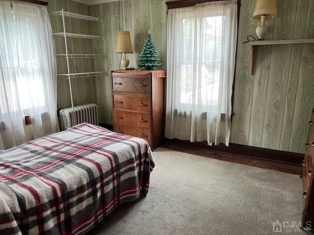 bedroom featuring wood walls and radiator heating unit