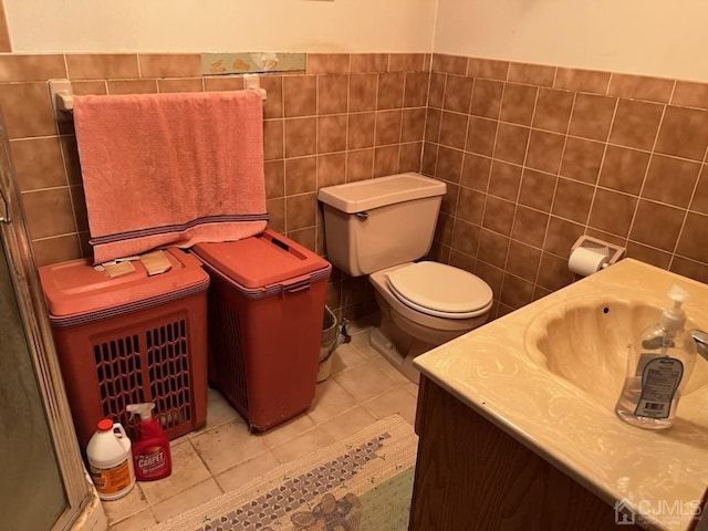 bathroom with tile patterned flooring, vanity, toilet, and tile walls