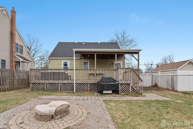 rear view of property featuring a fenced backyard, a shingled roof, a yard, and a deck