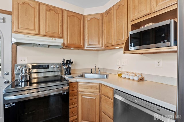 kitchen featuring light brown cabinetry, a sink, light countertops, under cabinet range hood, and stainless steel appliances