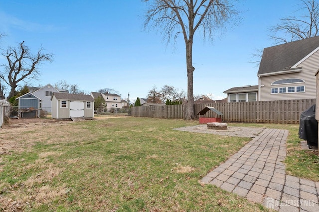 view of yard featuring an outbuilding, a fire pit, a fenced backyard, and a storage unit