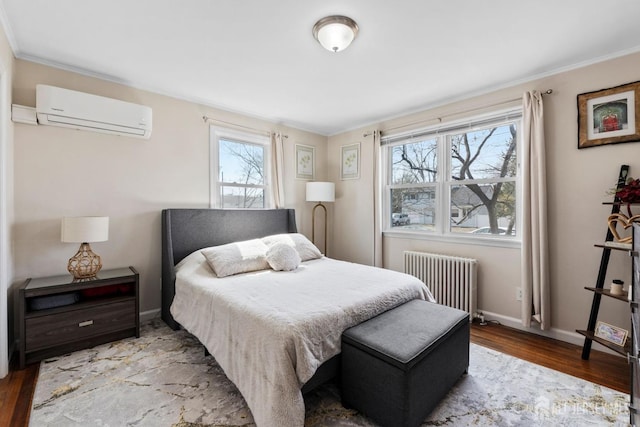 bedroom featuring an AC wall unit, baseboards, radiator, and wood finished floors