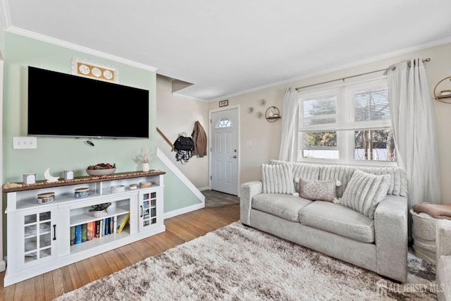 living area with baseboards, ornamental molding, wood finished floors, and stairway